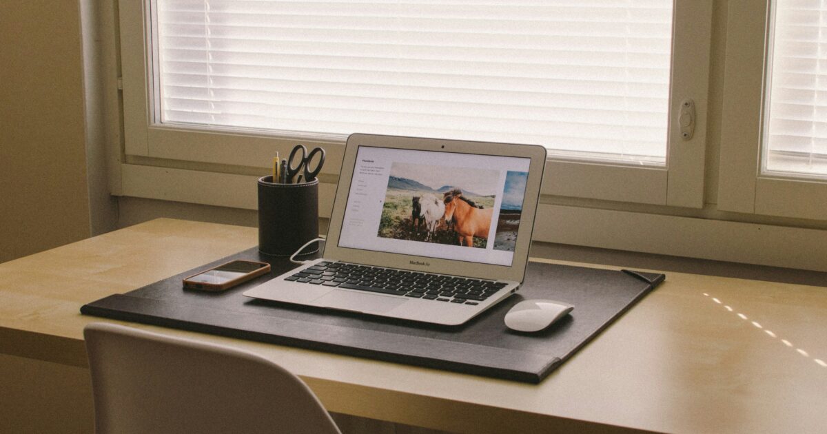 木製デスクの上に置かれたノートパソコンに馬の写真が表示されている様子