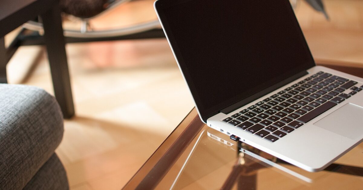 ガラスのテーブルに置かれた電源オフ状態のノートパソコンとモダンな室内