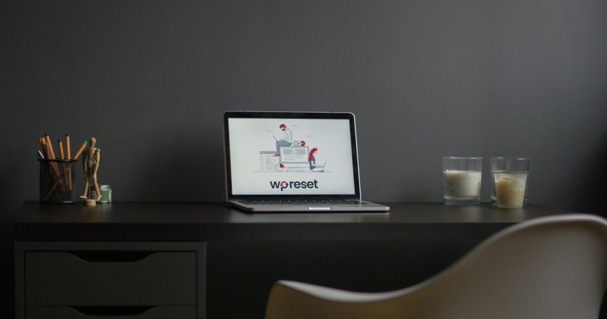 暗い部屋のデスク上に置かれたノートパソコンにWP Resetのロゴが表示されている様子