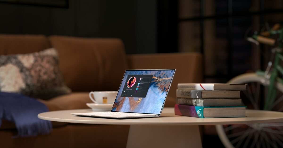 リビングのテーブルに置かれたノートパソコンと積み重ねられた本とコーヒーカップ